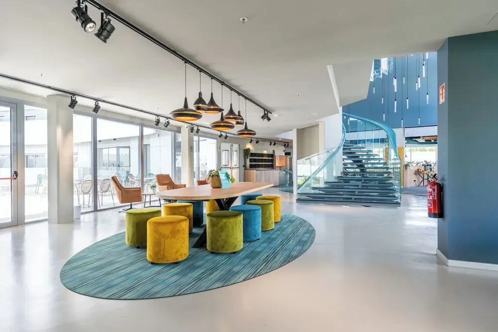 Espace de détente lumineux avec table ronde et assises colorées.