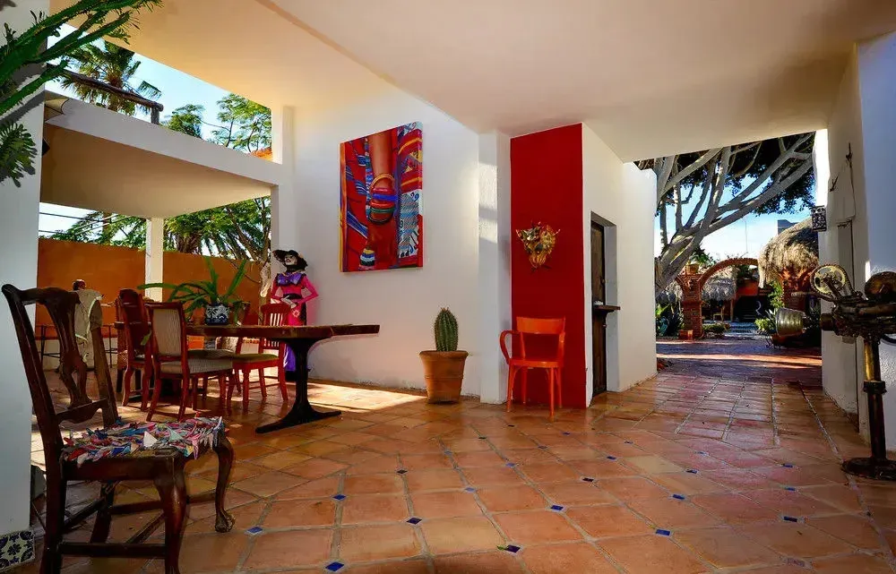Espace extérieur ombragé avec table à manger et décorations murales colorées.