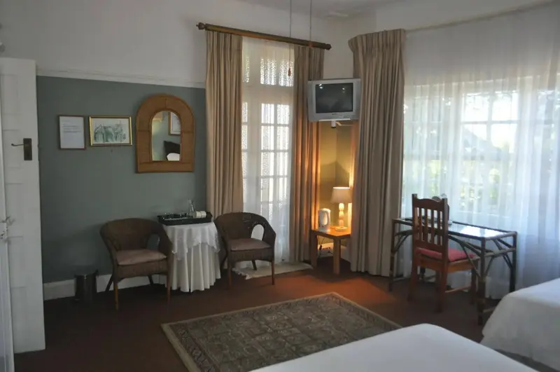 Une chambre lumineuse avec deux fauteuils et un bureau près d'une fenêtre.