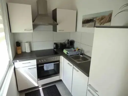 Une cuisine équipée avec des meubles blancs et un plan de travail gris.