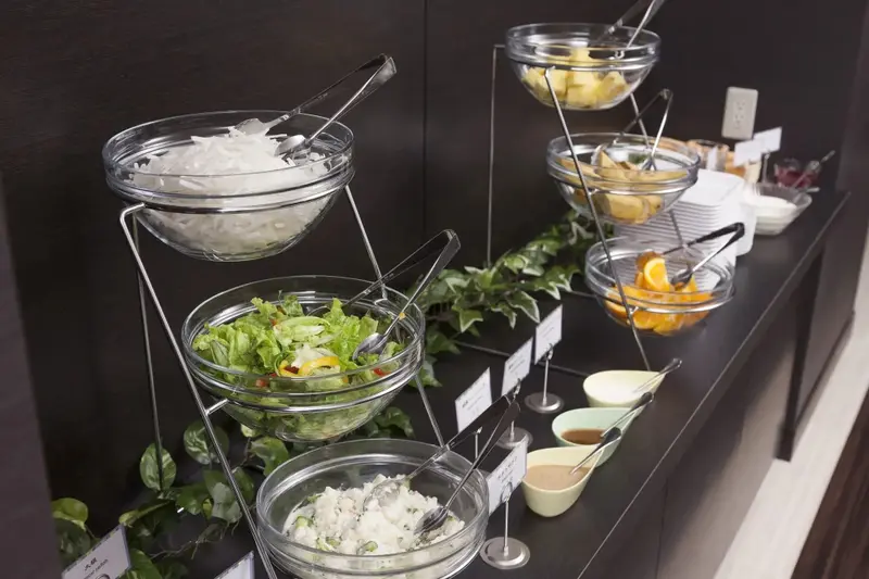 Présentation de salades fraîches et de fruits variés sur un buffet.