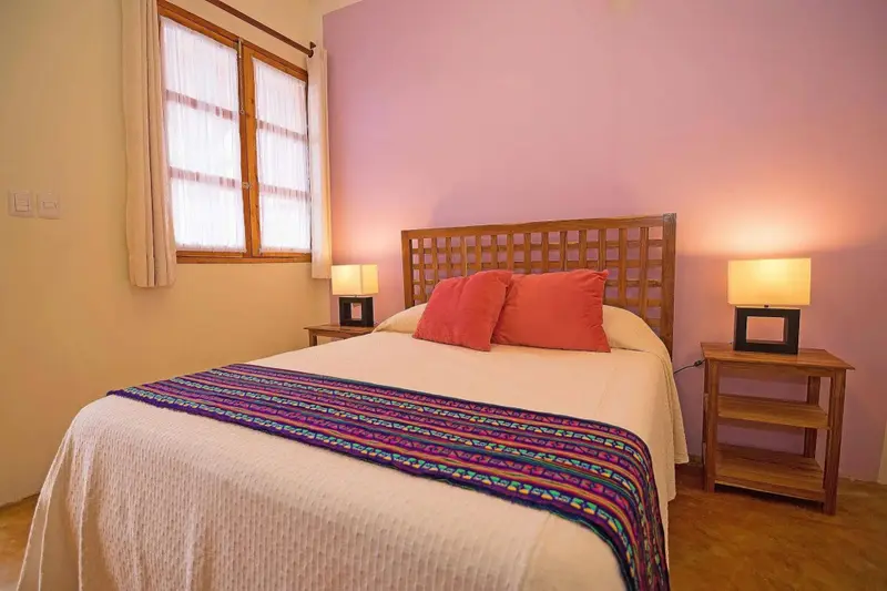 Une chambre lumineuse avec un lit double et des tables de chevet.