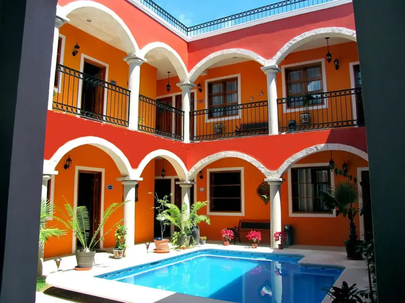 Une cour intérieure colorée avec une piscine et des balcons ornés de fer forgé.