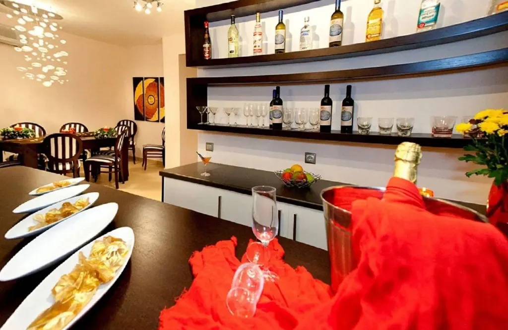 Une table dressée avec des assiettes de chips et des boissons, dans une salle lumineuse avec un bar bien garni.