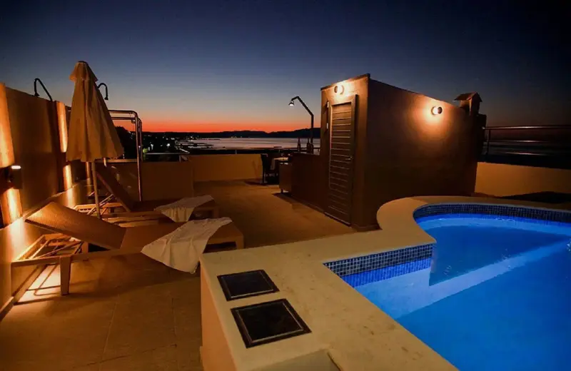 Terrasse avec piscine et mobilier de détente au coucher du soleil.
