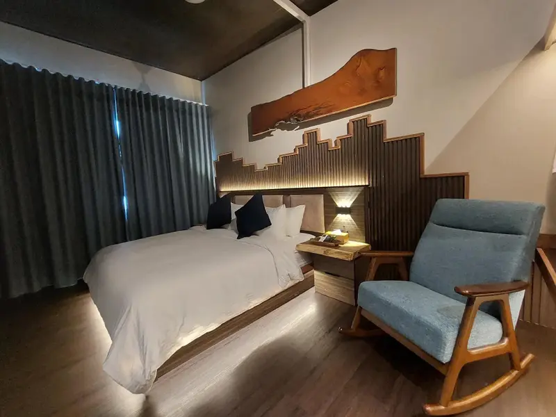 Une chambre à coucher lumineuse avec un grand lit et un fauteuil à bascule.