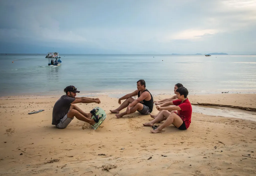 Des personnes sont assises sur une plage de sable fin face à la mer.