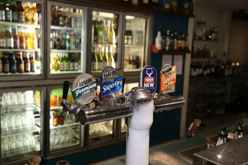 Un comptoir de bar avec des robinets et des bouteilles en arrière-plan.