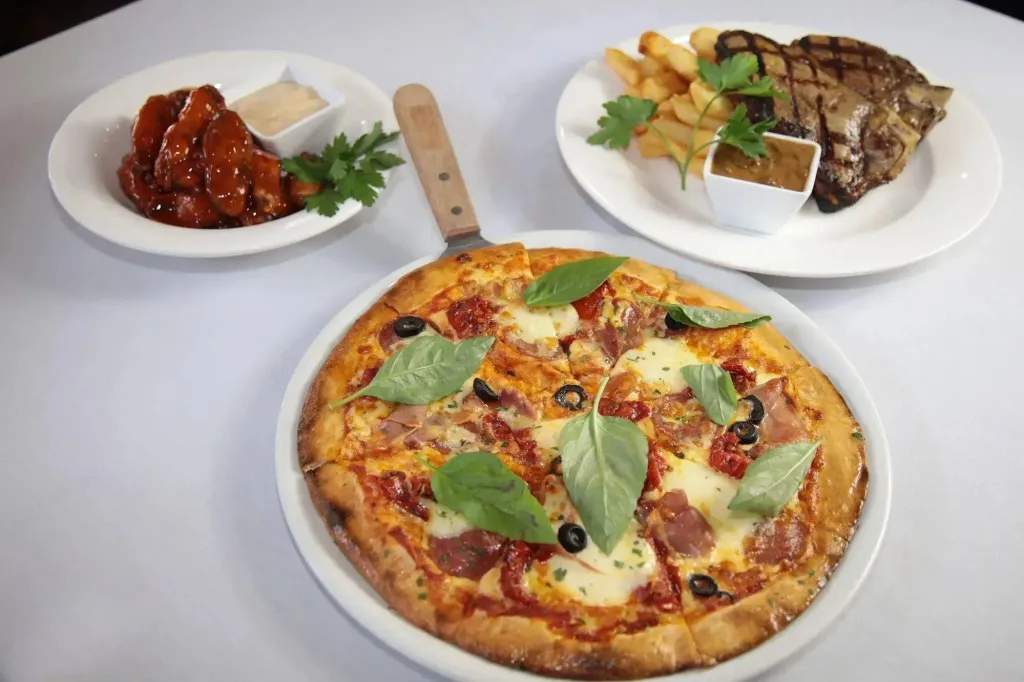 Une pizza garnie et deux accompagnements sont présentés sur une table.
