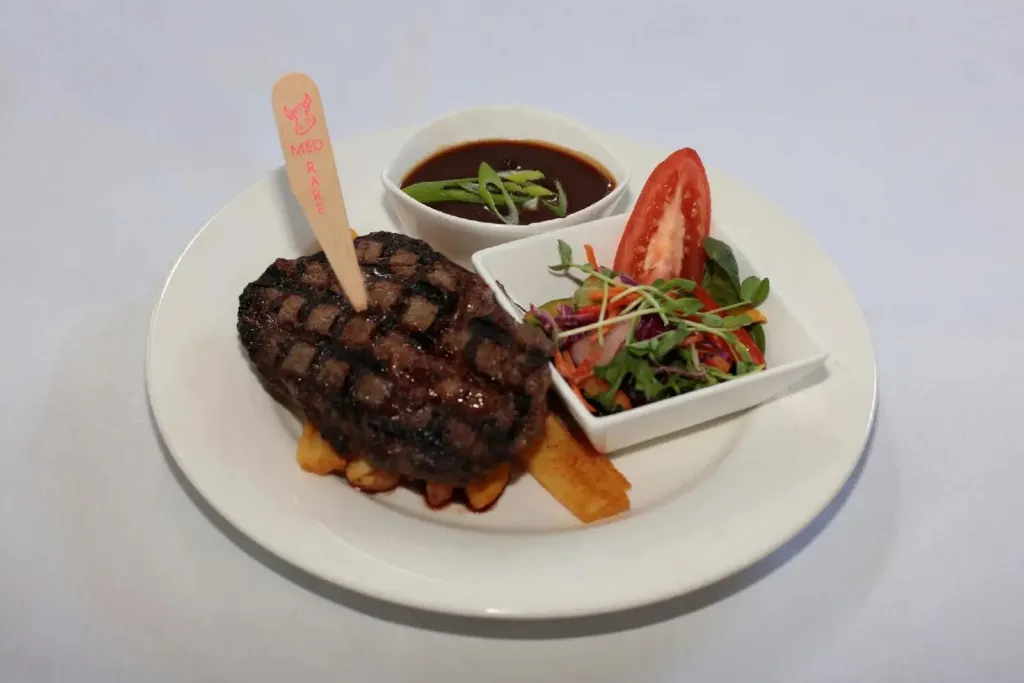 Assiette de viande grillée accompagnée de légumes et de sauce.