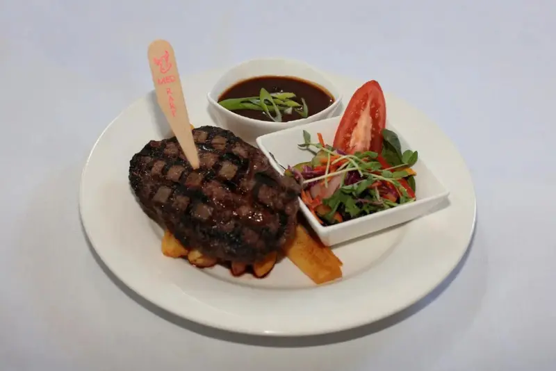 Assiette de viande grillée accompagnée de légumes et de sauce.