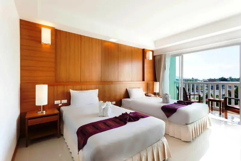 Une chambre lumineuse avec deux lits simples et une vue sur l'extérieur.