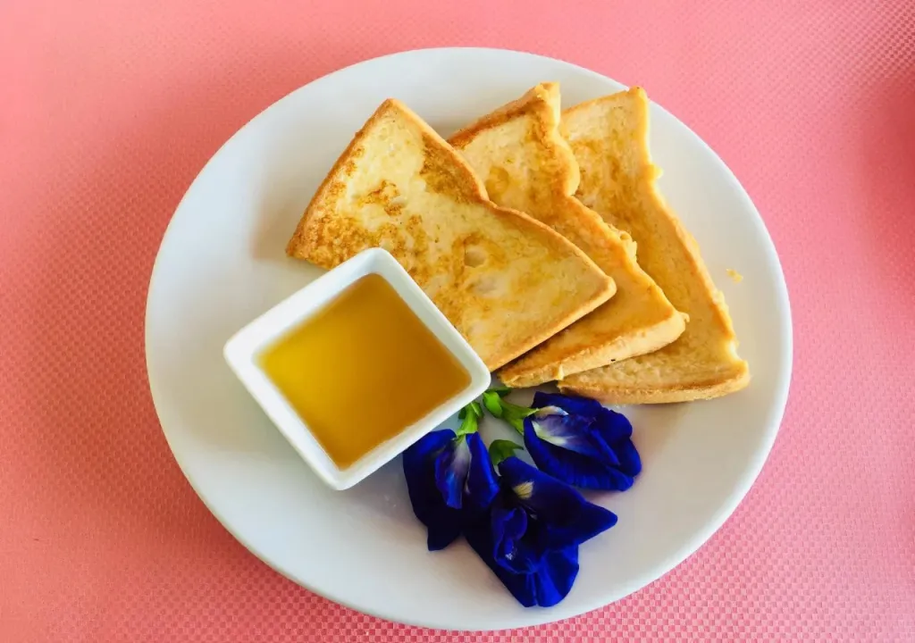 Assiette de beignets dorés accompagnés d'une sauce et d'une fleur.