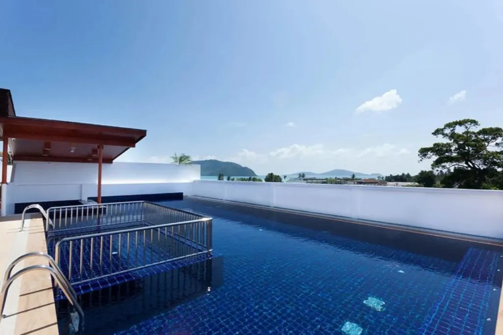 Piscine rectangulaire sur un toit-terrasse ensoleillé avec vue sur la mer.