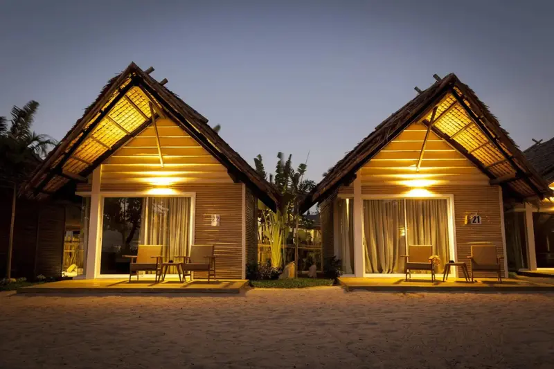 Deux bungalows éclairés avec terrasse et mobilier de jardin.