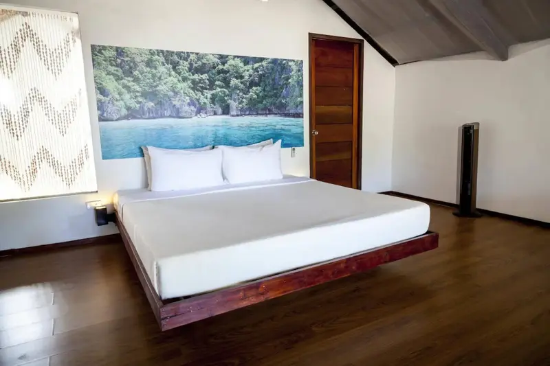 Une chambre lumineuse avec un grand lit face à une décoration murale représentant une plage.