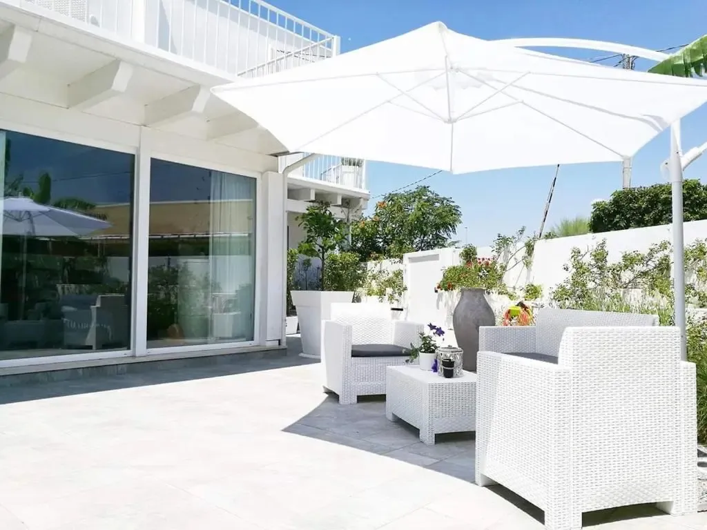 Terrasse aménagée avec mobilier blanc et parasol tendu.