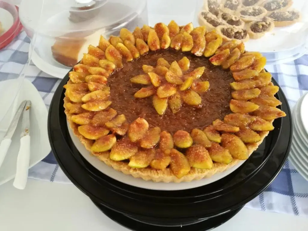 Une tarte aux figues décorée est présentée sur un présentoir.