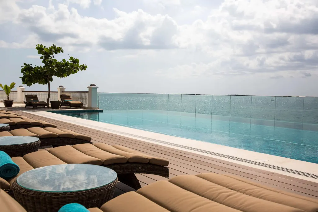 Transats et piscine à débordement avec vue sur la mer.