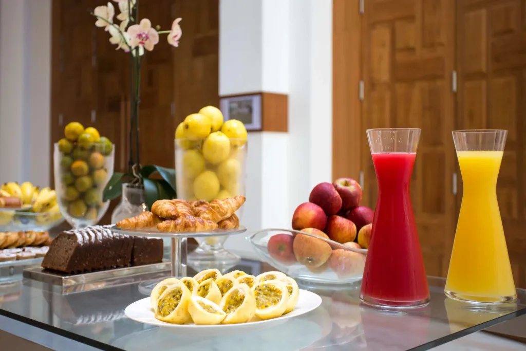 Une table basse présente une variété de pâtisseries, de fruits frais et de jus colorés.
