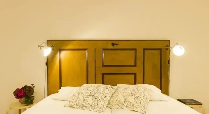 Un lit recouvert d'une courtepointe blanche et de coussins décoratifs se trouve devant une tête de lit originale en porte.