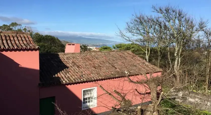 Toits en tuiles rouges d'une habitation avec vue sur un paysage montagneux et la mer.