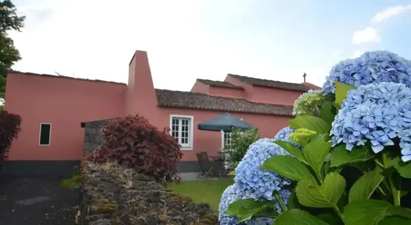 Bâtiment rose avec jardin fleuri au premier plan.