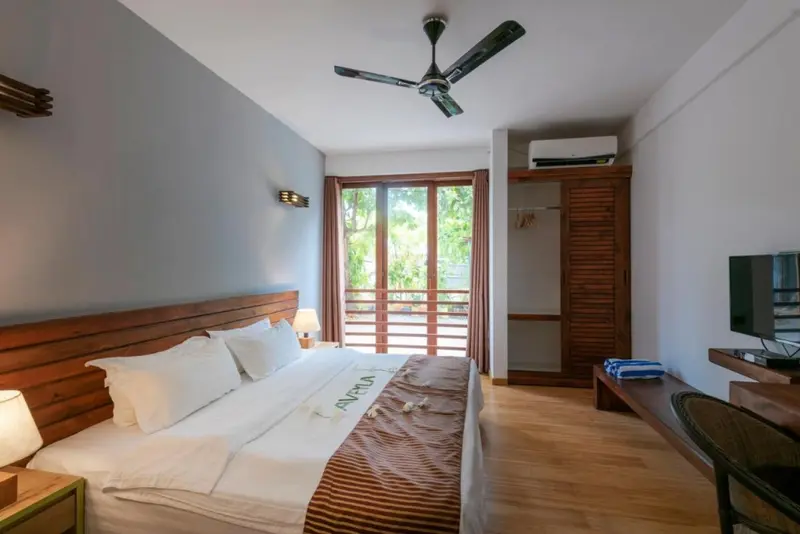 Une chambre lumineuse avec un lit fait et un accès à une terrasse.