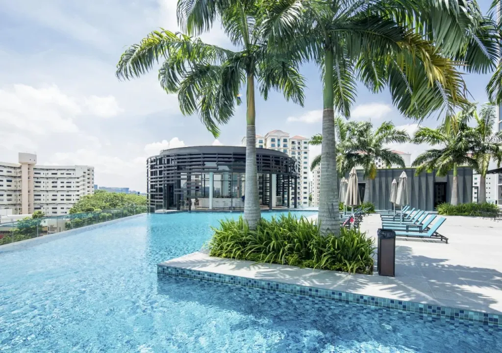 Une piscine bleue bordée d'une terrasse avec des transats et des palmiers.