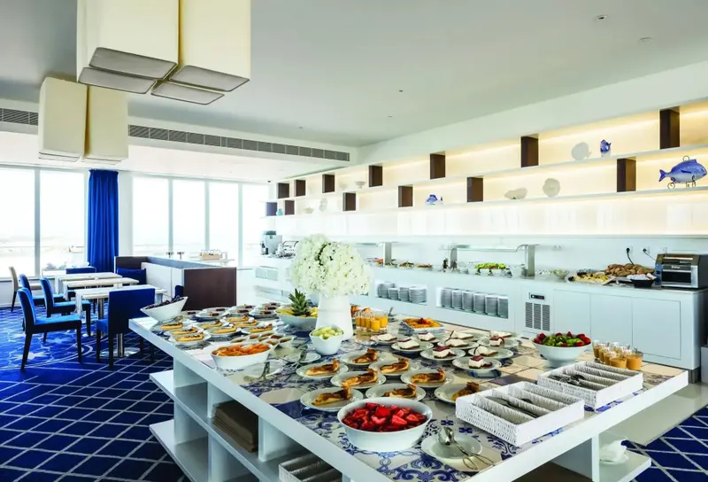 Un buffet propose une grande variété de plats et de boissons dans une salle lumineuse.