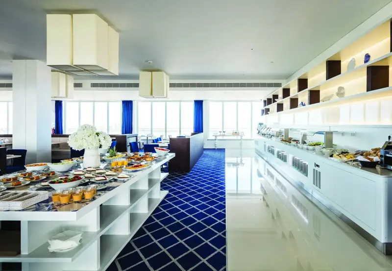 Une salle lumineuse présente un long buffet garni de plats variés.