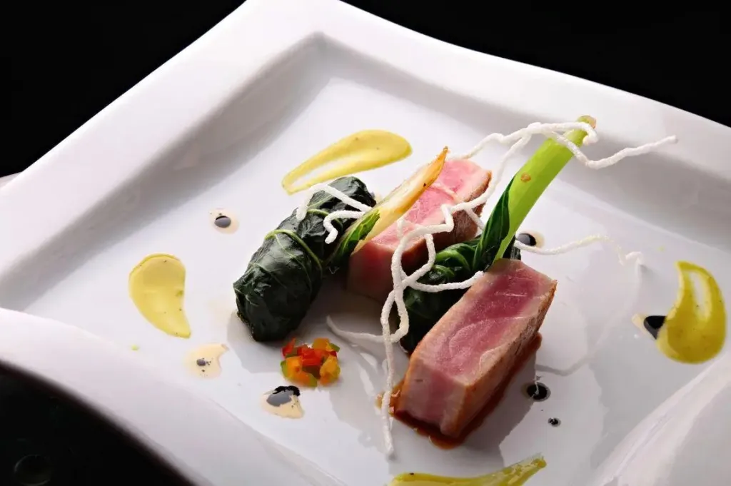 Assiette raffinée avec des morceaux de poisson et des légumes.
