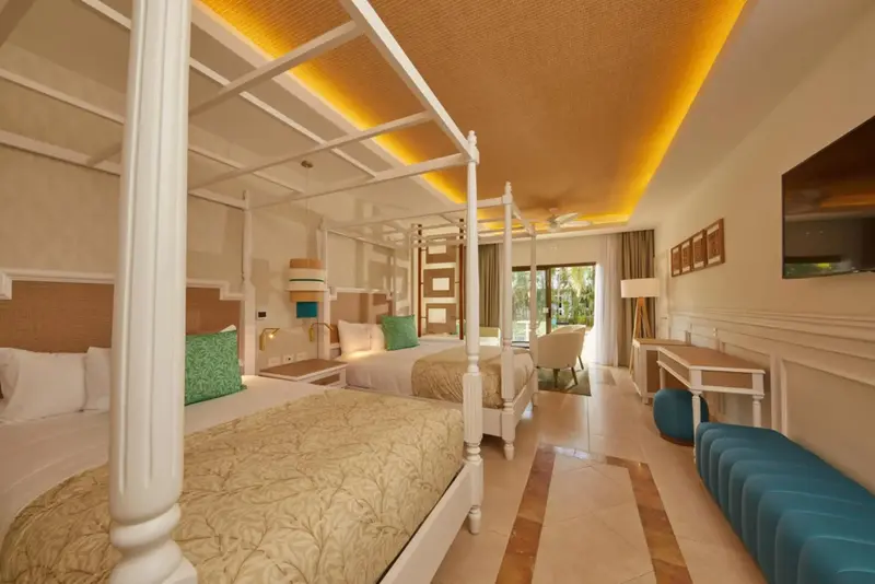 Une chambre lumineuse avec deux lits à baldaquin et un coin salon.