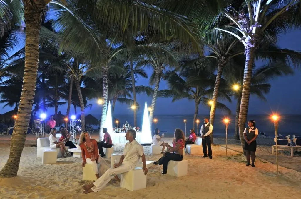 Des personnes sont assises et se détendent sur une plage éclairée au crépuscule.