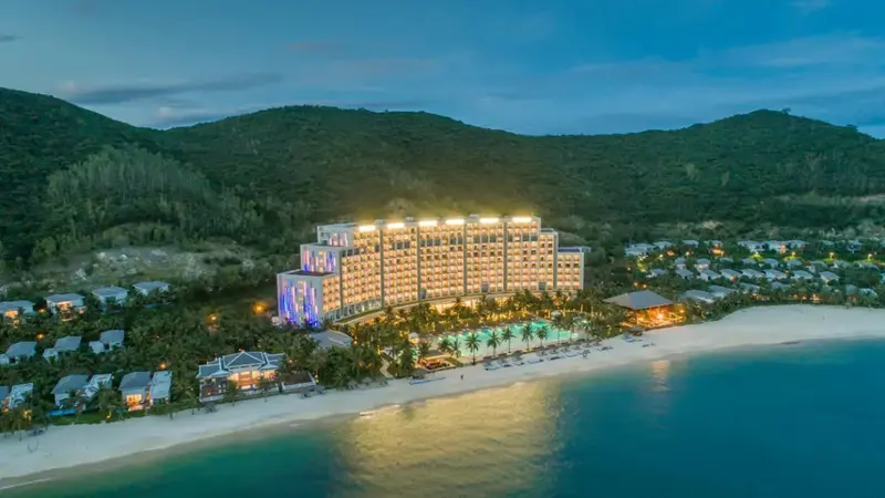 Vue aérienne d'un complexe hôtelier illuminé au bord d'une plage de sable fin.
