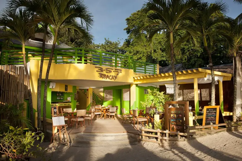 Terrasse ombragée avec tables et chaises en bord de plage.