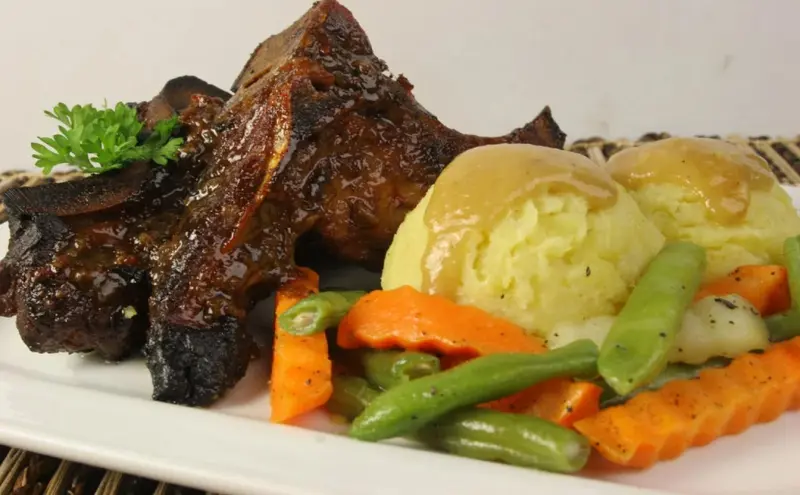 Assiette de viande grillée accompagnée de légumes et de purée.