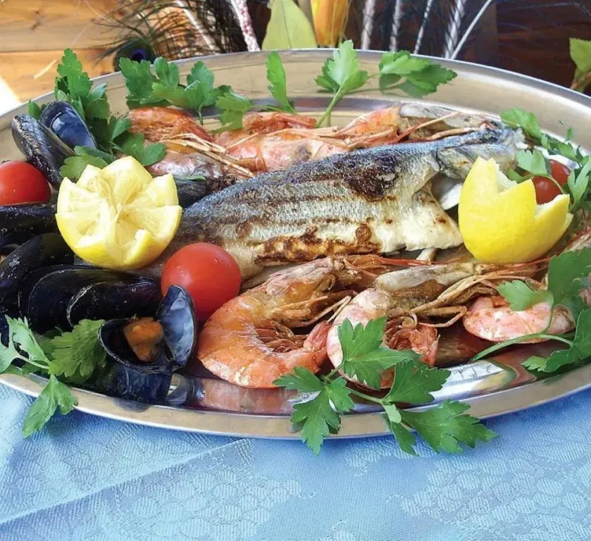 Assiette généreuse de fruits de mer grillés, décorée de citron et de persil.