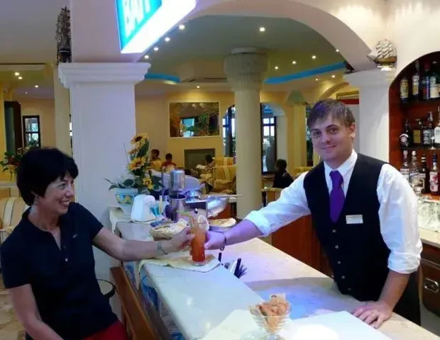 Un barman sert une boisson à une cliente souriante.