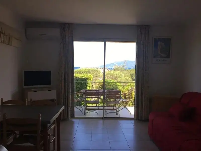 Une pièce de vie lumineuse s'ouvre sur une terrasse avec vue sur la végétation et la mer.