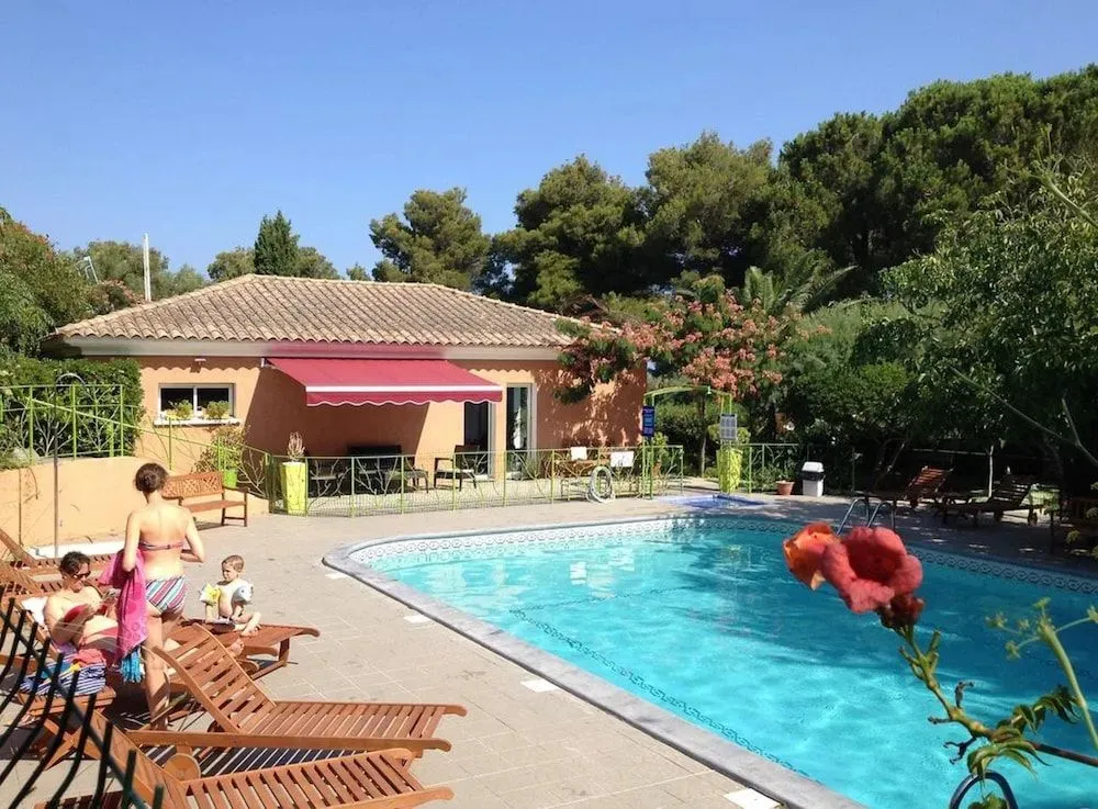 Une piscine ensoleillée avec des transats et un bâtiment à l'arrière-plan.