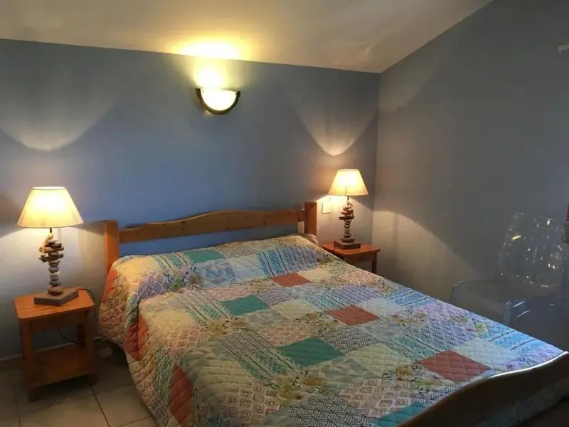 Une chambre lumineuse avec un grand lit recouvert d'une courtepointe colorée.