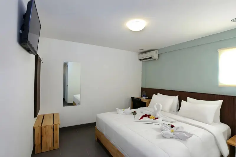 Une chambre lumineuse avec un grand lit recouvert de draps blancs et décoré de fleurs.