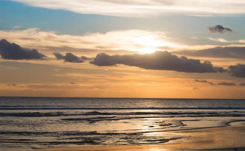 Ciel nuageux au coucher du soleil sur une plage.