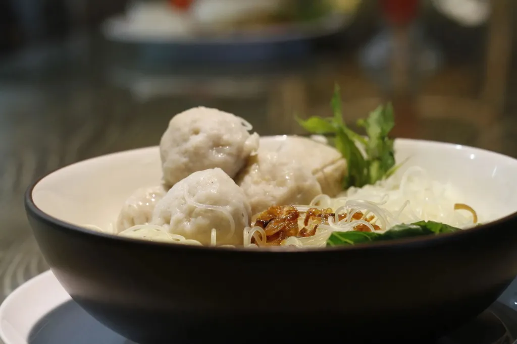 Un bol de nouilles garni de boulettes de viande et d'herbes aromatiques.