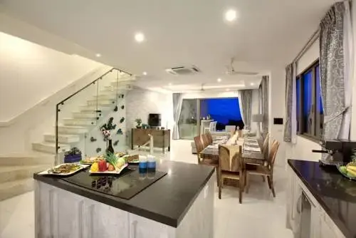 Une table est dressée dans une pièce lumineuse avec une cuisine ouverte et un escalier moderne.