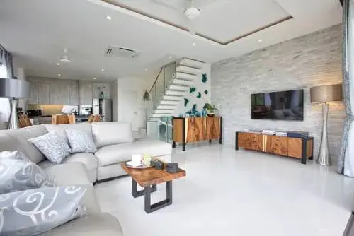 Un espace de vie lumineux avec un canapé, un meuble bas et un escalier.