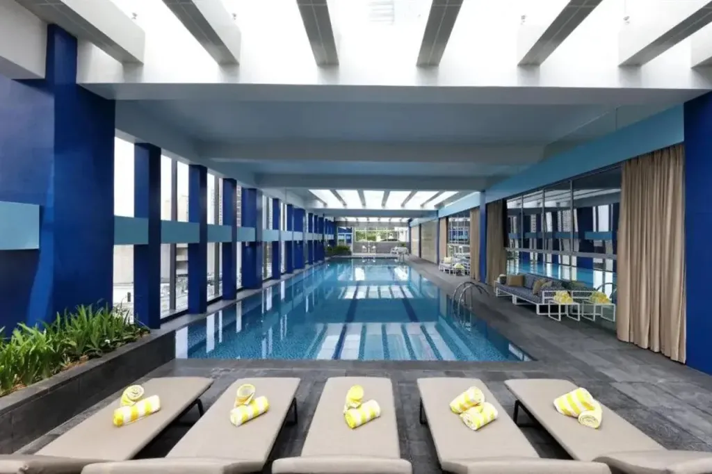 Une piscine intérieure rectangulaire avec des transats et des serviettes jaunes.
