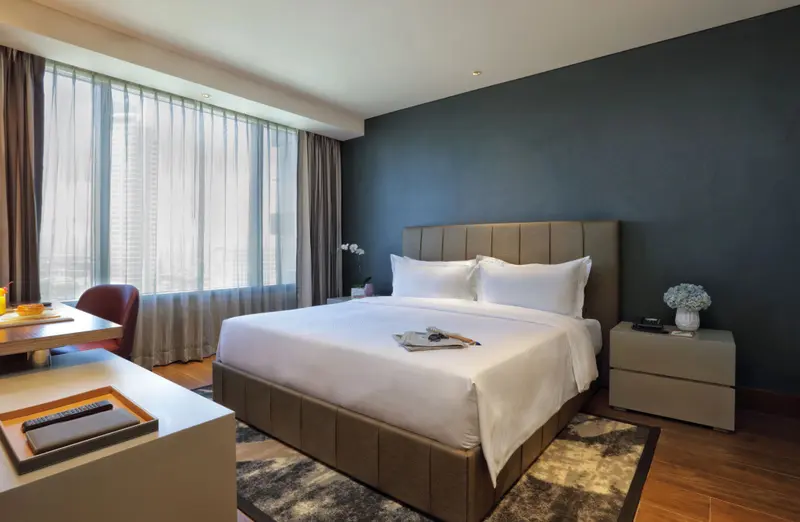 Une chambre lumineuse avec un grand lit et un bureau près de la fenêtre.