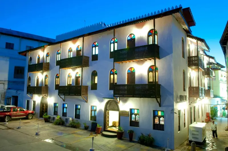 Bâtiment blanc à deux étages avec des fenêtres en arc et des balcons en bois.